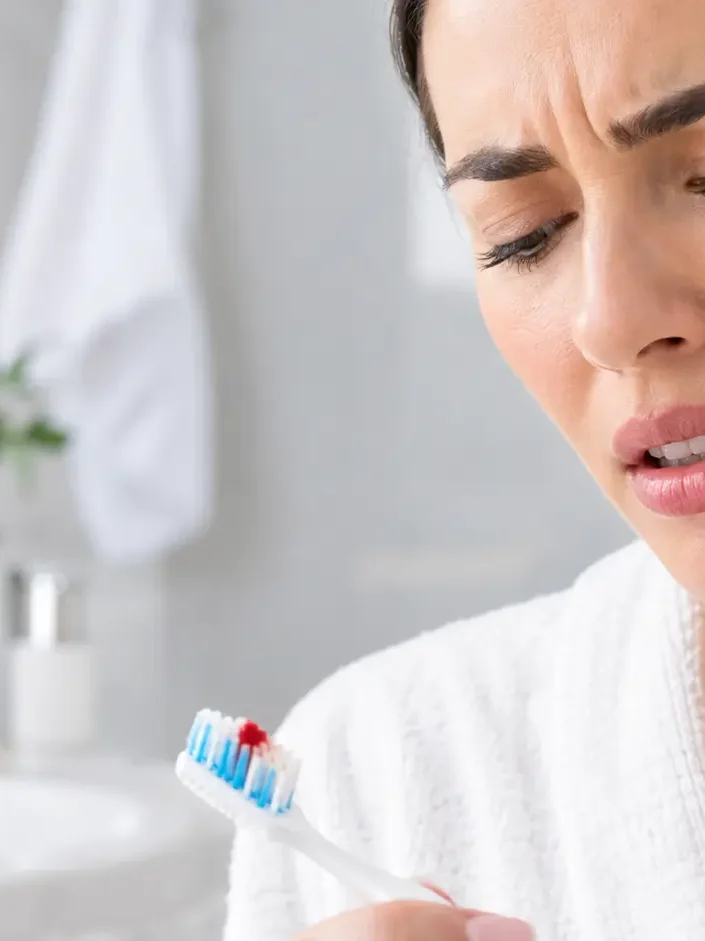 Mulher preocupada examina escova de dentes com sangue - gengivite e periodontite